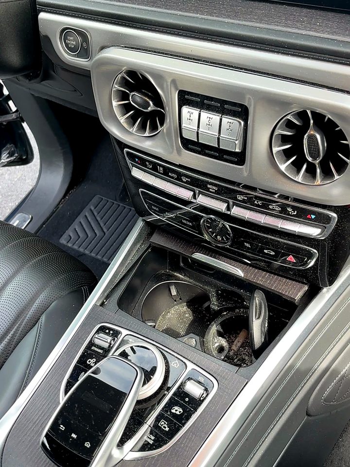Mercedes-AMG G63 center console with grit and debris in the cupholders before an interior detail.