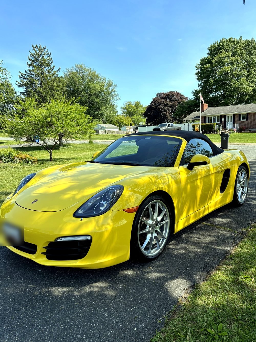 Yellow Porsche Boxster convertible shining in a sunny Harford County driveway after a mobile detail.