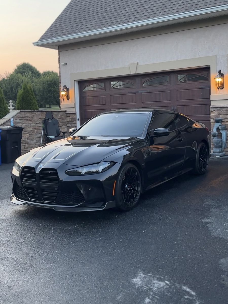 Black BMW M4 coupe on a freshly washed driveway at sunset after a mobile detail.