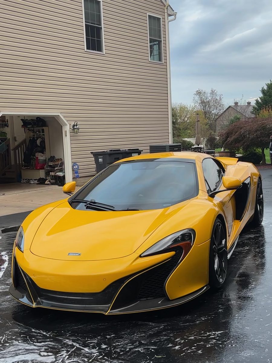 Yellow McLaren 650S on a wet driveway after a mobile exterior detail.