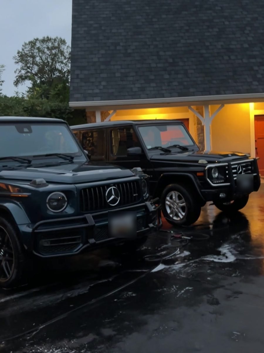 Two black Mercedes G-Class SUVs detailed in the same driveway at dusk.