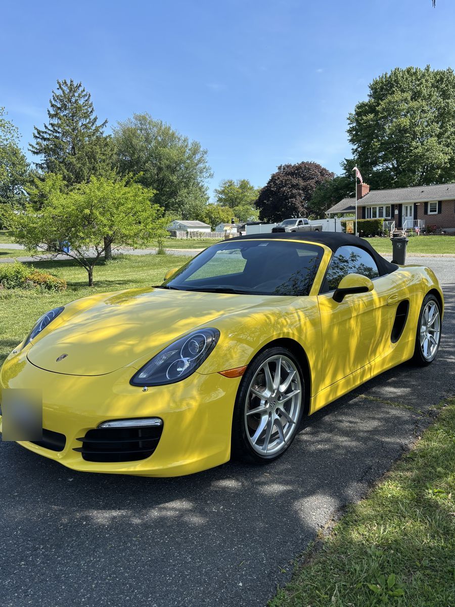 Yellow Porsche Boxster convertible gleaming in a driveway after an exterior detail.